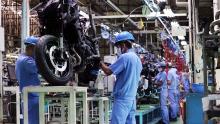 Yamaha Motors factory assembly line with workers in safety gear working on motor cycle